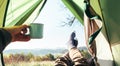 Freedom feeling. Traveler looks from tent on mountain hills panorama and mug of tea