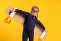 Freedom, girl playing to be airplane pilot, funny little girl with aviator cap and glasses, carries wings made of brown Royalty Free Stock Photo