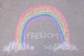 freedom inscription and a rainbow drawn on the asphalt with chalk, a symbol of the lgbt community, crayons on the ground