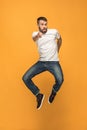 Freedom in moving. handsome young man jumping against orange background Royalty Free Stock Photo