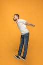 Freedom in moving. handsome young man jumping against orange background Royalty Free Stock Photo