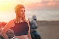 Freedom and travel. Portrait of young independent caucasian woman. Golden sunset and motorcycle in the background. The