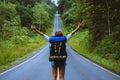 Freedom traveler woman standing with raised arms and enjoying a beautiful nature On a country road. woman with backpack travel In Royalty Free Stock Photo