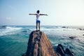 woman outstretched arms on seaside rock cliff edge