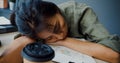 Freelance Asia exhausted lady hard work sleeping with many a paper coffee cup on wooden table at office. Working from living room Royalty Free Stock Photo