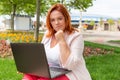 Freelance. Caucasian thoughtful woman working at a laptop in a Park. Plus size model. Concept of remote work and online business Royalty Free Stock Photo