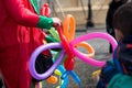 A freelance clown creating balloon animals and different shapes at outdoor festival in city center. Royalty Free Stock Photo