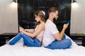 Man and woman sitting back to back on bed in bedroom together Royalty Free Stock Photo