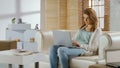 Freelance girl typing on laptop sitting on sofa, comfortable working conditions