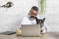 Freelance man working from home with his dog sitting in the office. Man using a laptop at home with a cute dog Royalty Free Stock Photo