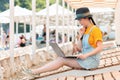 Freelance. Portrait of young woman sits on a sunbed and thoughtfully works at a laptop. Sun beds and umbrellas on the beach in the Royalty Free Stock Photo