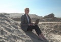 Freelance and remote work.business woman in stylish business suit with laptop sitting in desert sand. Female student