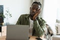 Freelance stress concept. Overworked sad black man sitting at workplace and napping while working on laptop computer Royalty Free Stock Photo