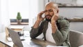 Freelance stress. Tired mature latin man looking at laptop screen and rubbing temples, sitting at desk at home Royalty Free Stock Photo