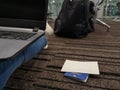 Freelance traveler is working on a laptop, and next to him is a passport and a ticket on the floor in the waiting room of a Royalty Free Stock Photo