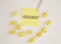 Freelance word on yellow paper on white table, top view