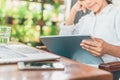 Freelance work. Casual dressed man sitting at wooden desk inside garden working on computer pointing with color pen electronic Royalty Free Stock Photo