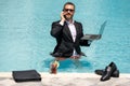 Freelance work, distance online work, e-working. Summer business. Business man in suit remote working on laptop in pool