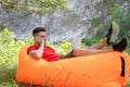 Freelance work or study concept. young man using laptop and talking on smartphone. sitting in inflatable chair on grass Royalty Free Stock Photo