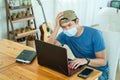 Freelance young man wearing face mask working with laptop computer and feeling sad about failing to invest online in the stock Royalty Free Stock Photo