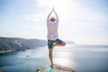 A digital nomad, a man in a hat, a businessman does yoga on the rocks by the sea at sunset time, does a business