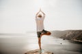 A digital nomad, a man in a hat, a businessman does yoga on the rocks by the sea at sunset time, does a business