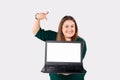 Freelancer. Caucasian smiling woman holds a laptop, pointing at the mock up screen with index finger. Plus size model Royalty Free Stock Photo