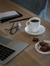 Freelancer desktop with laptop, notes, glasses, coffee cup and cookies Royalty Free Stock Photo