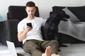 Freelancer guy with laptop and dog is working at home in quarantine to coronavirus infection Royalty Free Stock Photo
