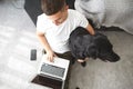 Freelancer guy with laptop and dog is working at home in quarantine to coronavirus infection Royalty Free Stock Photo