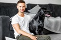 freelancer guy sitting at home working with a dog in an embrace, black labrador. Royalty Free Stock Photo