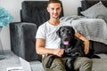 freelancer guy sitting at home working with a dog in an embrace, black labrador. Royalty Free Stock Photo