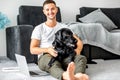 freelancer guy sitting at home working with a dog in an embrace, black labrador.