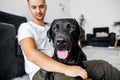 freelancer guy sitting at home working with a dog in an embrace, black labrador. Royalty Free Stock Photo