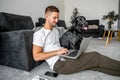 Freelancer guy sitting at home working in laptop and with dog in