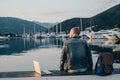 Freelancer with laptop resting time and enjoy sunset on the shore near the yacht boat at rest