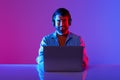 freelancer man with headset working on laptop in neon studio Royalty Free Stock Photo