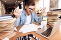 Freelancer man looking at notes frustrated at laptop sitting at desk surrounded by books. Royalty Free Stock Photo