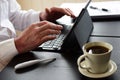 Freelancer man sits at a table and takes notes in a laptop.