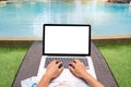 Freelancer using laptop working remotely near swimming pool. Young Asian traveler woman working on computer during her summer Royalty Free Stock Photo