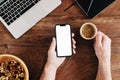 Freelancer using mobile phone with blank white mockup screen and drinking coffee at office desk Royalty Free Stock Photo