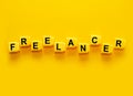 Freelancer - word made from yellow plastic blocks on a yellow background.