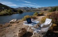 Freelancer working remotely from scenic lakeside location with laptop and folding chairs Royalty Free Stock Photo