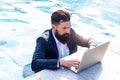 Freelancer working on vacation next to the swimming pool. Businessman using a computer in Pool. Funny Freelanc. Working Royalty Free Stock Photo