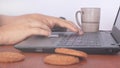 Freelancer works at a laptop and eats cookies at the workplace