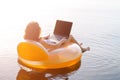 Freelancer works on a laptop sitting in an inflatable ring in th Royalty Free Stock Photo