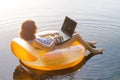 Freelancer works on a laptop sitting in an inflatable ring in th Royalty Free Stock Photo