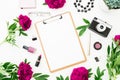 Freelancer workspace with clipboard, dairy, peony flowers and retro camera on white background. Flat lay, top view. Beauty blog co