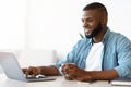 Freelancing Concept. Cheerful Black Freelancer Man Drinking Coffee And Working On Laptop Royalty Free Stock Photo
