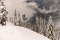 freeride snowboarder performs jump in the air over a snow-covered mountain slope